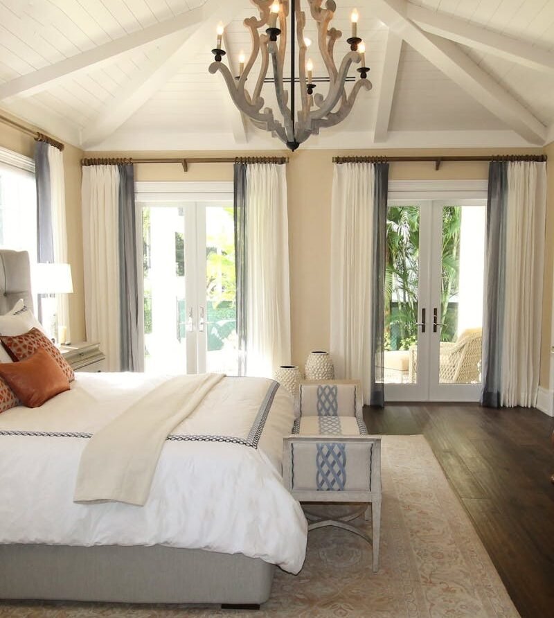 Stylish bedroom interior featuring a rustic chandelier, cozy bedding, and elegant wooden furniture.
