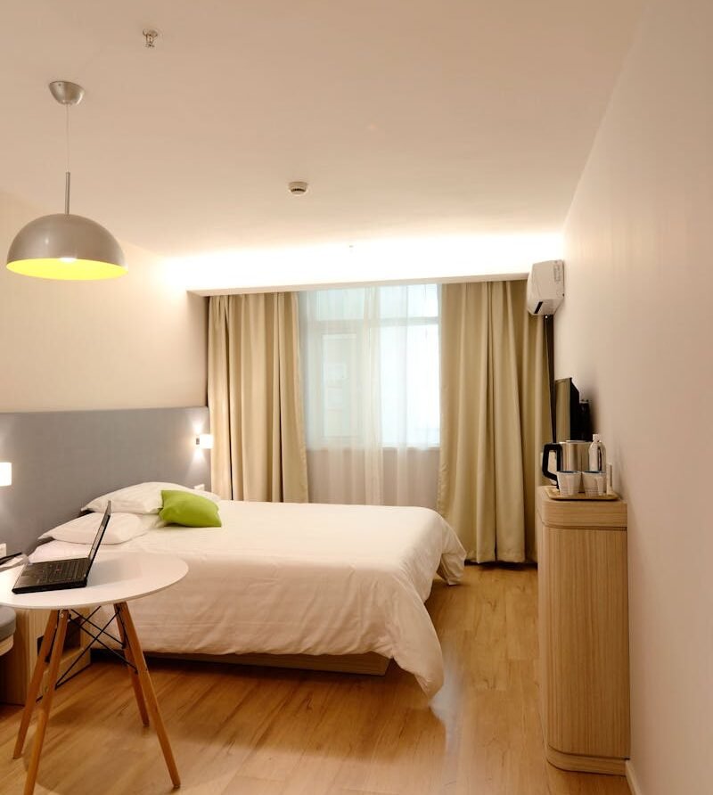 Spacious modern hotel room featuring cozy decor and neutral tones with natural light.