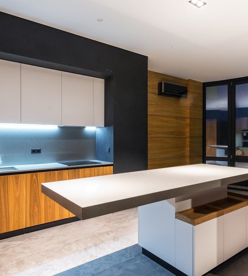 Interior of contemporary kitchen with huge windows against table and bright illumination in cooking zone